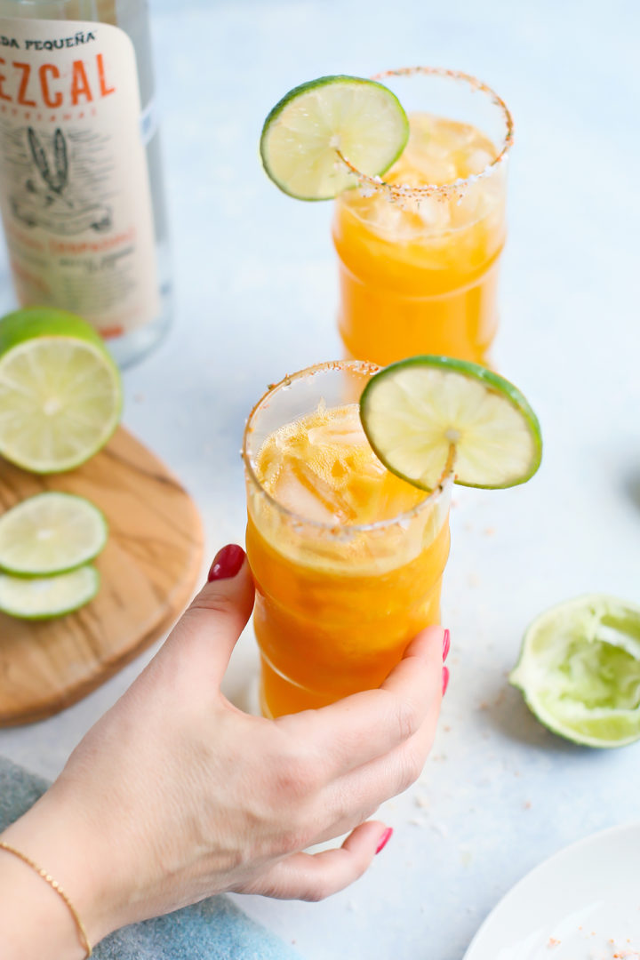 woman holding a glass of spicy passion fruit margarita