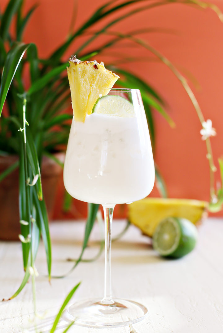 glass of shaken pina colada by a plant