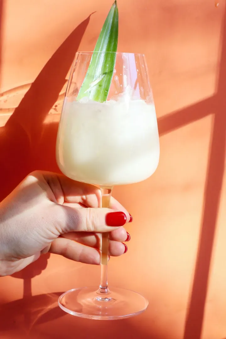 woman holding a glass of pina colada on the rocks
