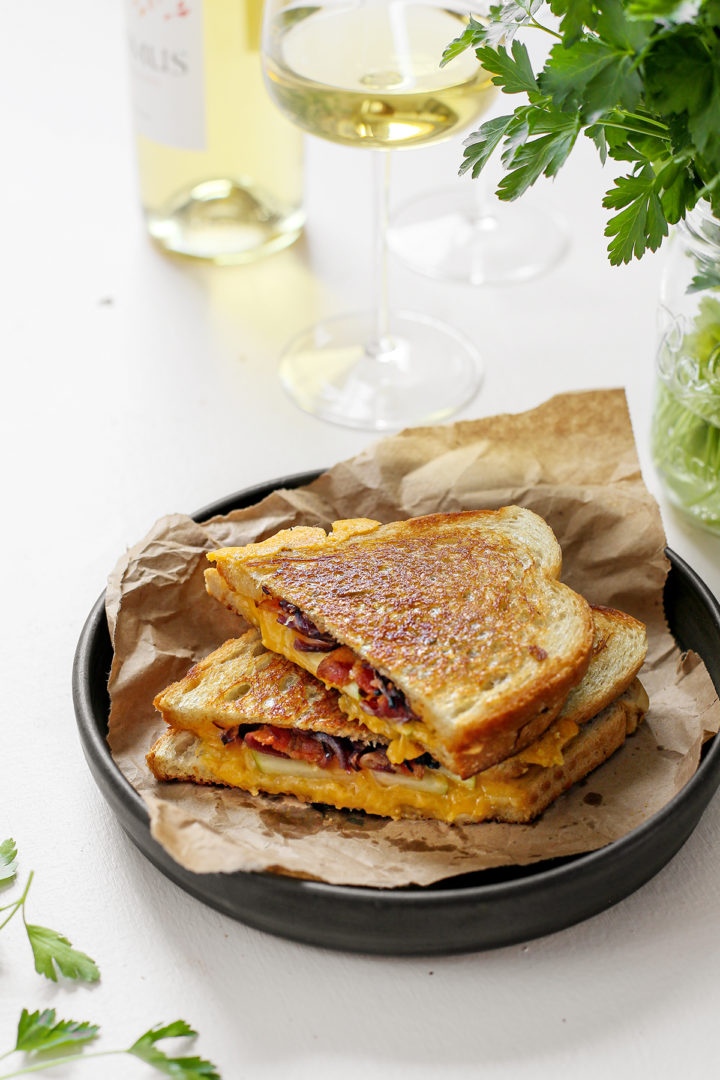 an apple and bacon grilled cheese sandwich being served on a black plate