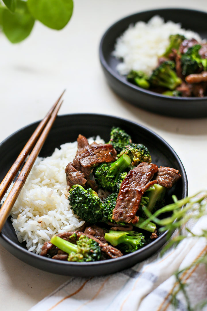 close up photo of rice with beef & broccoli on a black plate