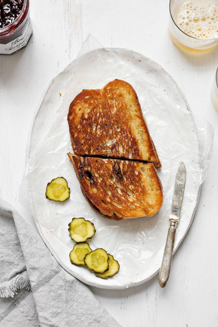 overhead image of a sliced brie grilled cheese on a platter with a knife