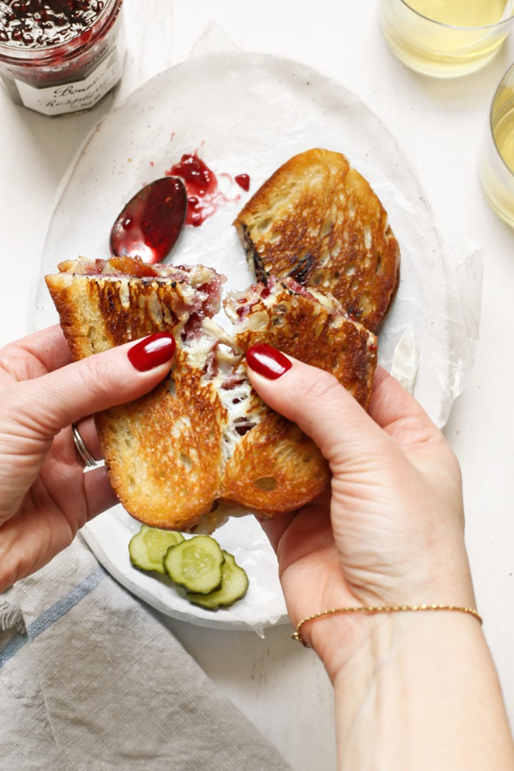 photo of a woman holding a brie grilled cheese sandwich before eating