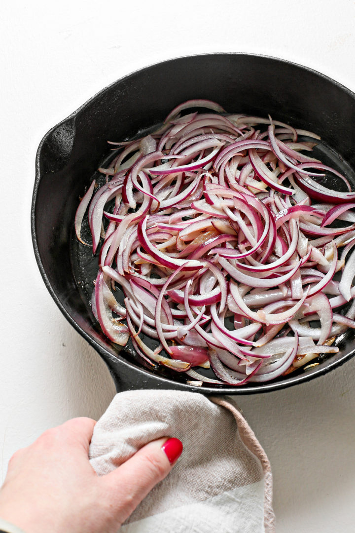 caramelized onions cooking in a cast iron pan for this bacon apple grilled cheese recipe