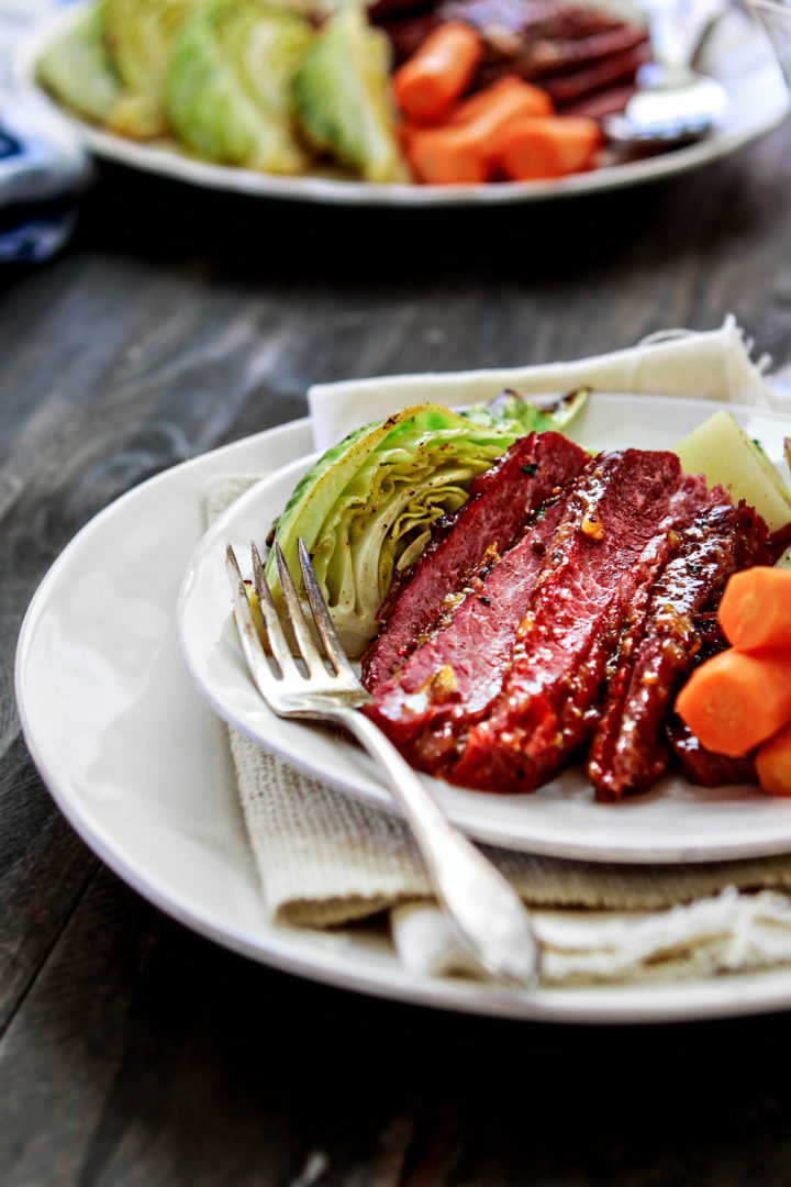 roasted cabbage, glazed honey mustard corned beef, and carrots served on a white plate for st patrick's day dinner menu