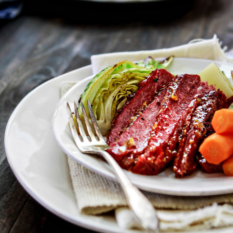 corned beef on a white plate with cabbage and carrots