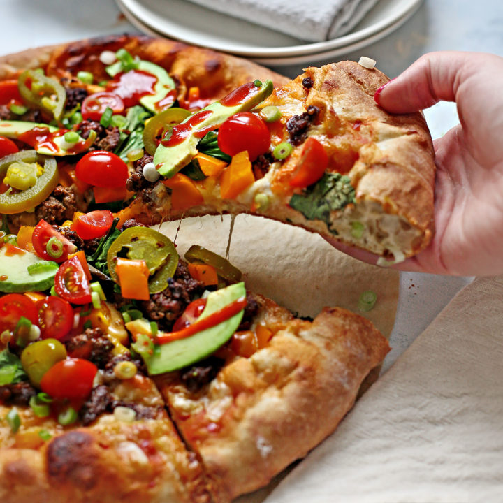 woman picking up a slice of taco pizza