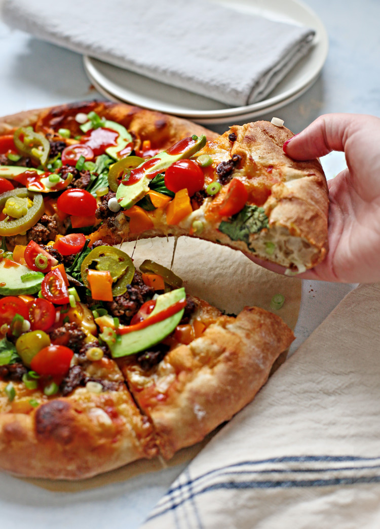 woman picking up a slice of taco pizza