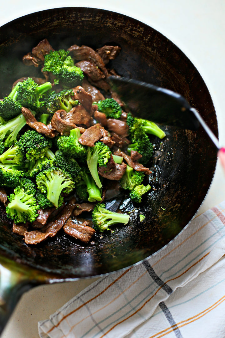 stirring the beef and broccoli together in a wok