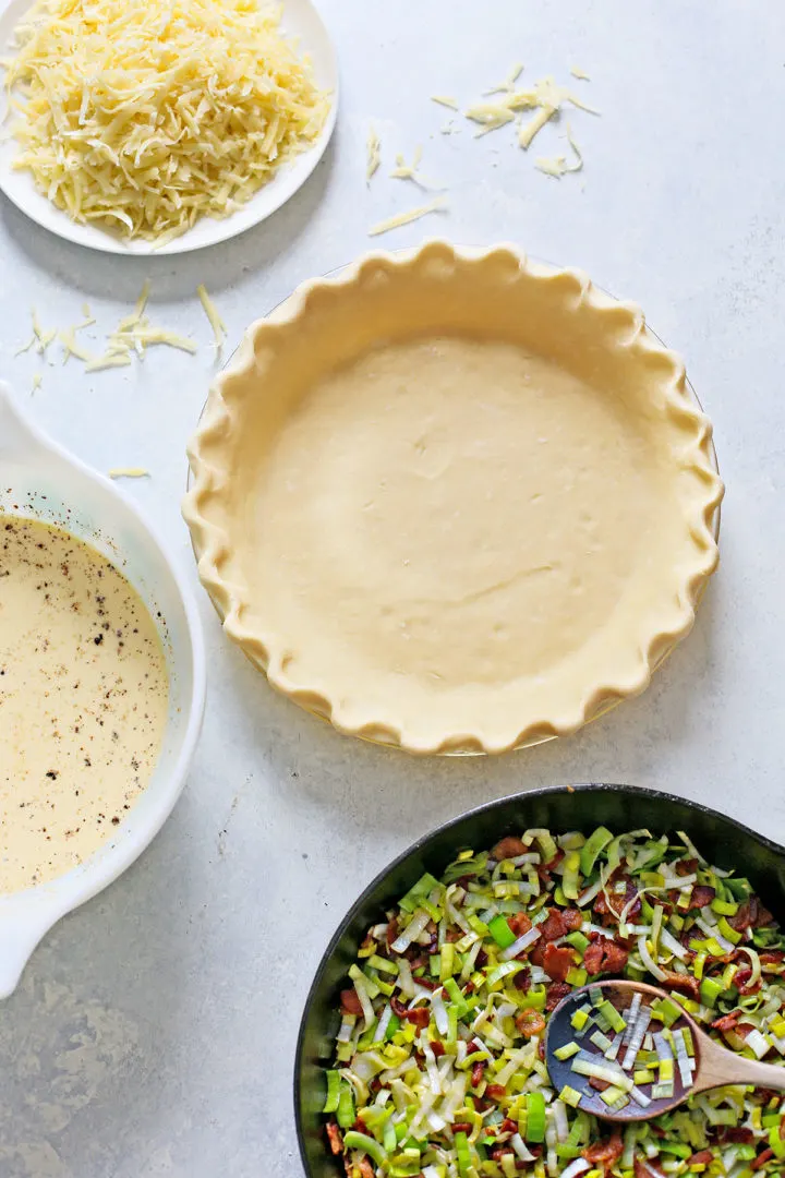 photo of a pie crust for a quiche and ingredients needed to make a recipe for quiche lorraine
