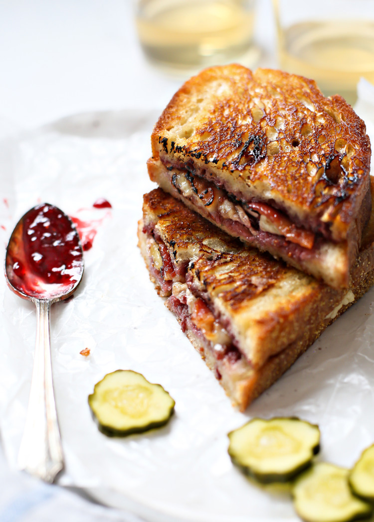 a brie grilled cheese cut in half and stacked next to pickle slices