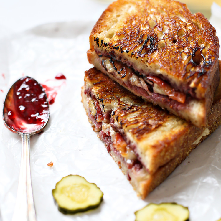 a brie grilled cheese cut in half and stacked next to pickle slices