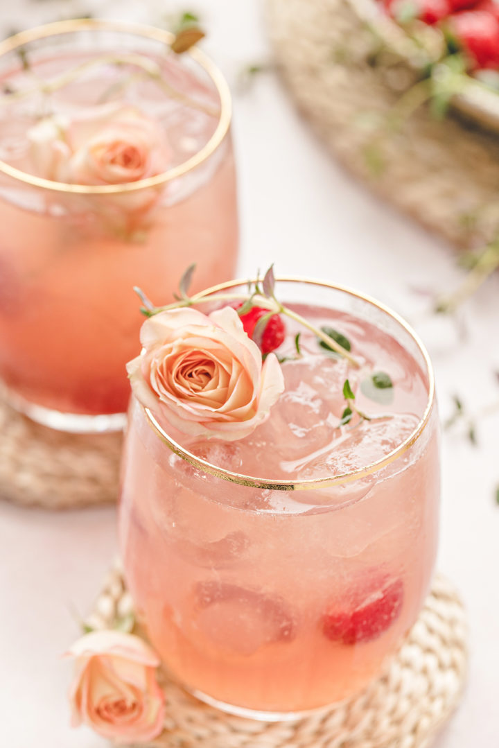 two glasses of this floradora cocktail (an easy simple gin cocktail) garnished with raspberries and roses