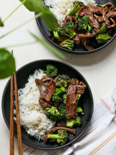 overhead photo of chinese beef and broccoli being served on two black plates