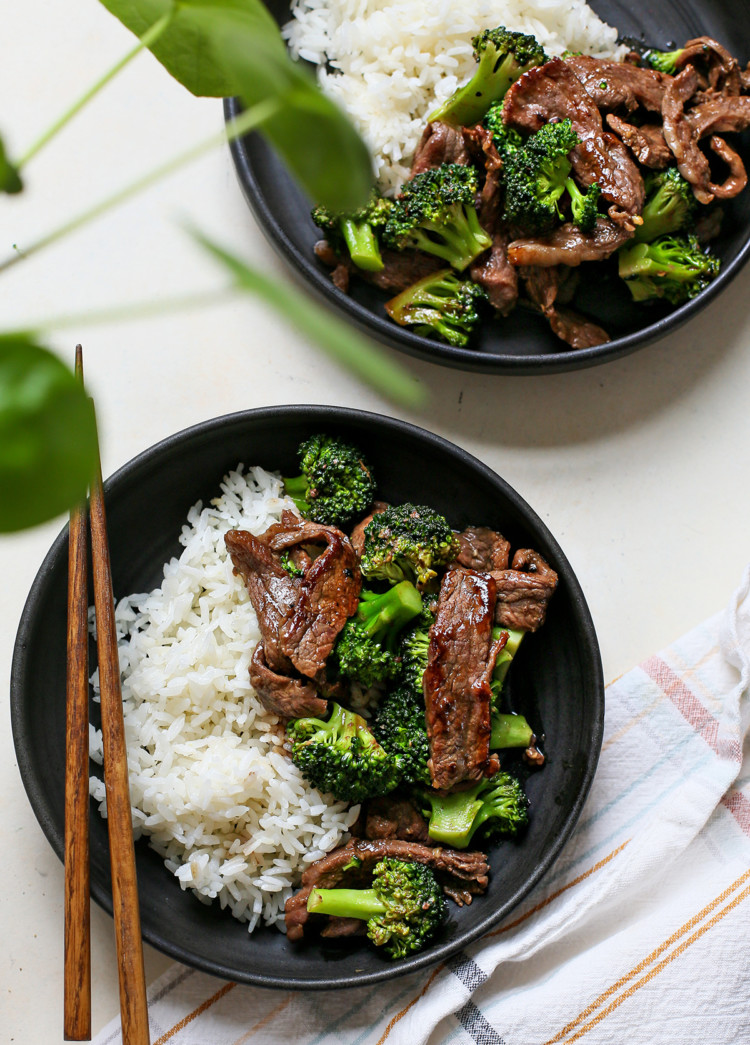 overhead photo of chinese beef and broccoli being served on two black plates
