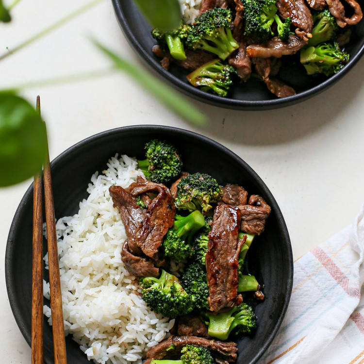 overhead photo of chinese beef and broccoli being served on two black plates