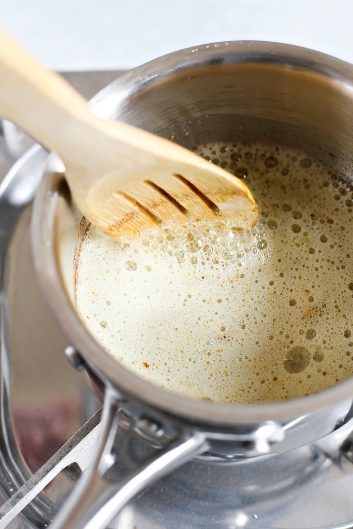 step 6 how to brown butter - woman stirring butter as it browns in a saucepan