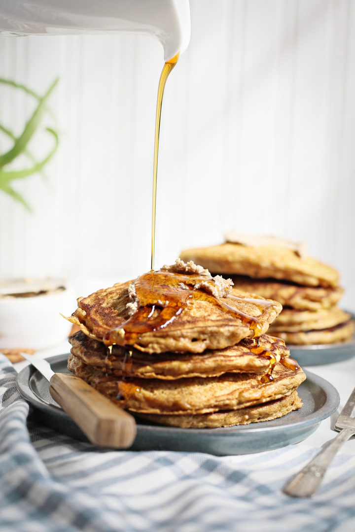 maple syrup pouring on top of a stack of carrot cake pancakes
