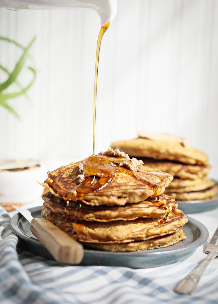 maple syrup pouring onto a stack of carrot pancakes on a dark blue plate
