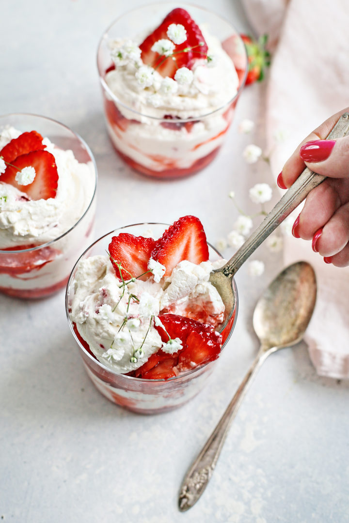 woman eating a dessert dish of strawberries and cream