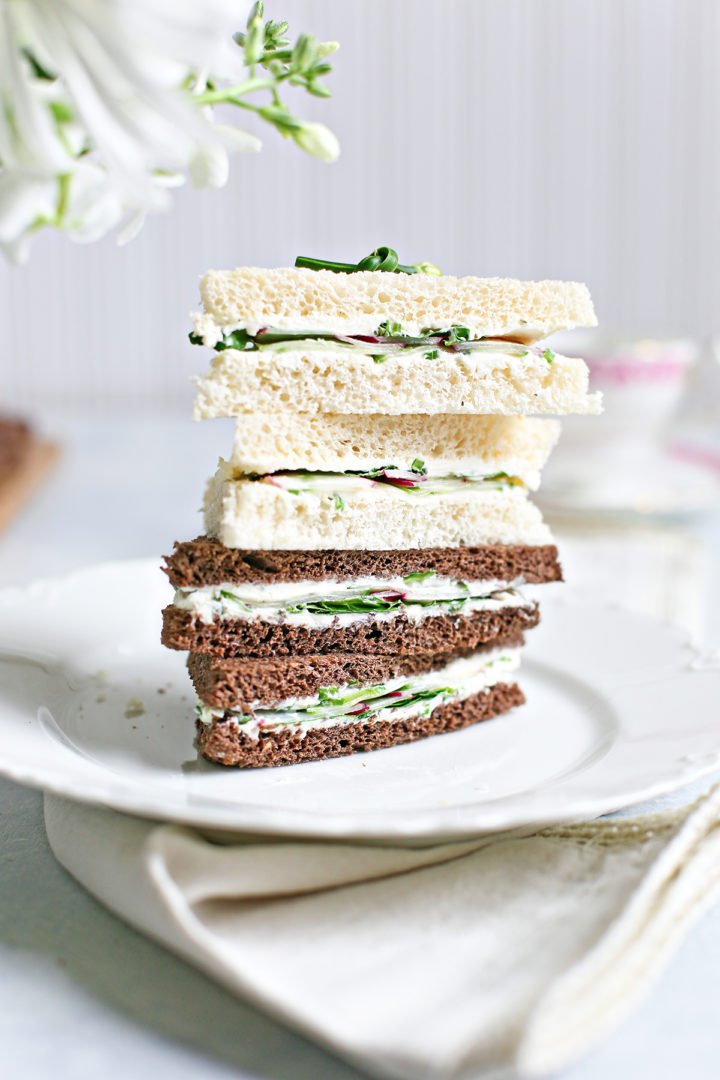 stack of watercress sandwiches cut in triangles on a white plate