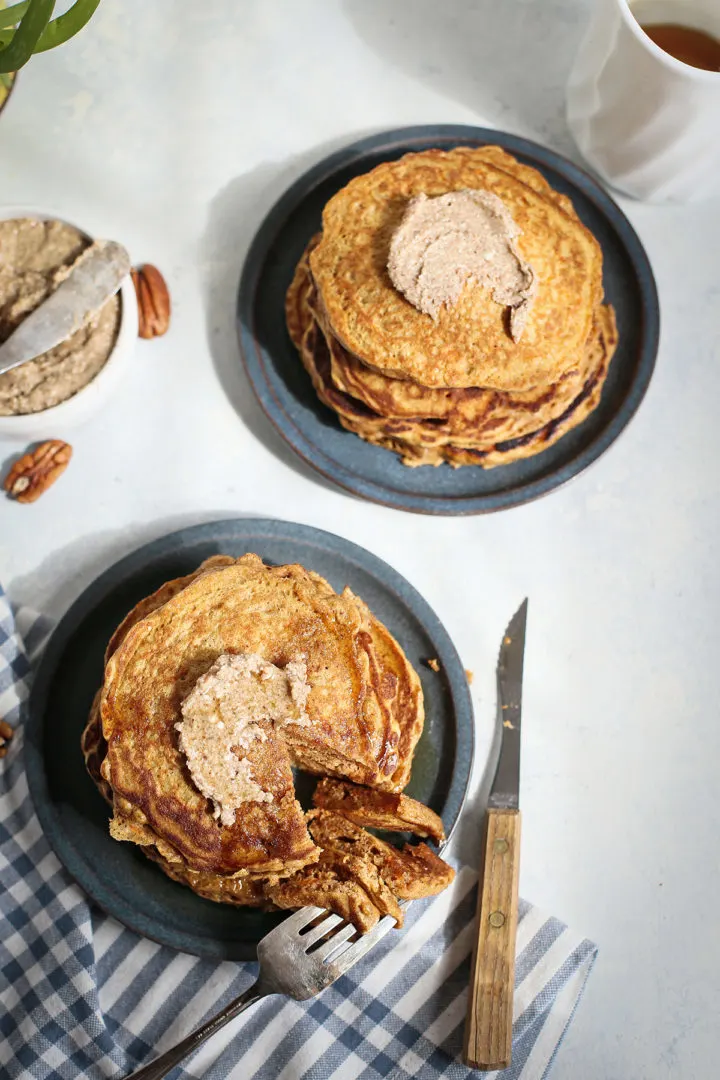 two plates of carrot cake pancakes, one with a fork cutting into the pancakes for a bite to eat