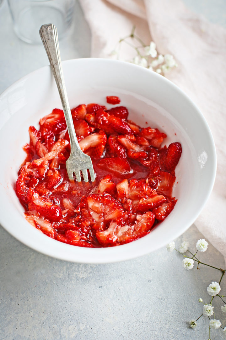 a white bowl of mashed strawberries for this strawberry with cream recipe