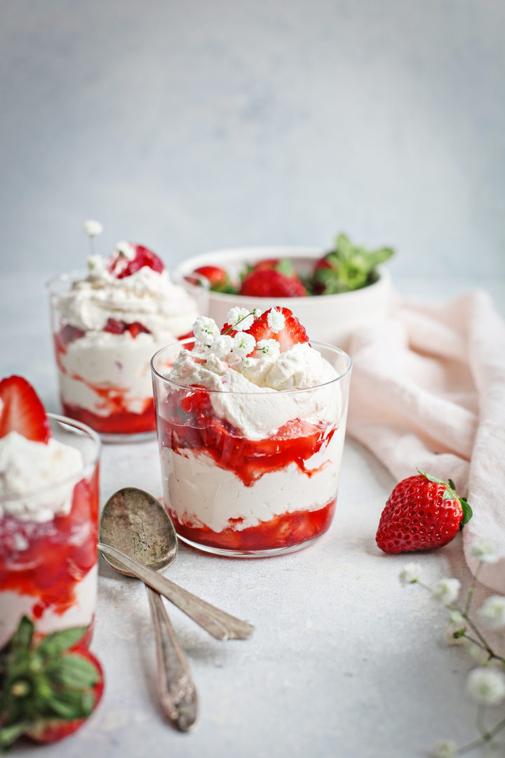 three clear dessert glasses filled with strawberries and cream - and easy strawberry dessert recipe