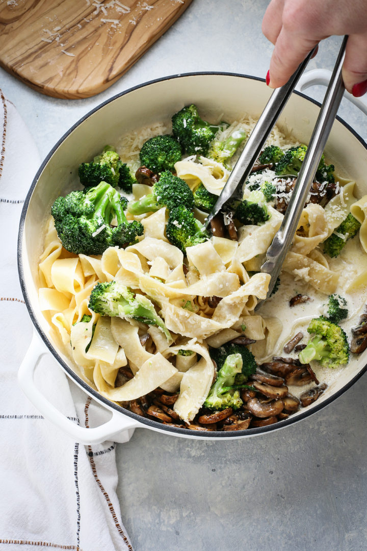 stirring together mushroom alfredo sauce and pasta