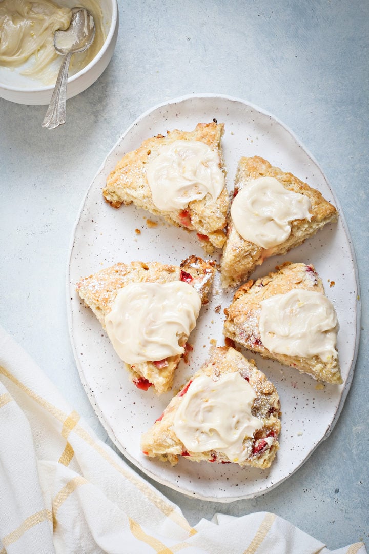 an oval serving plate of strawberry scones on a blue table