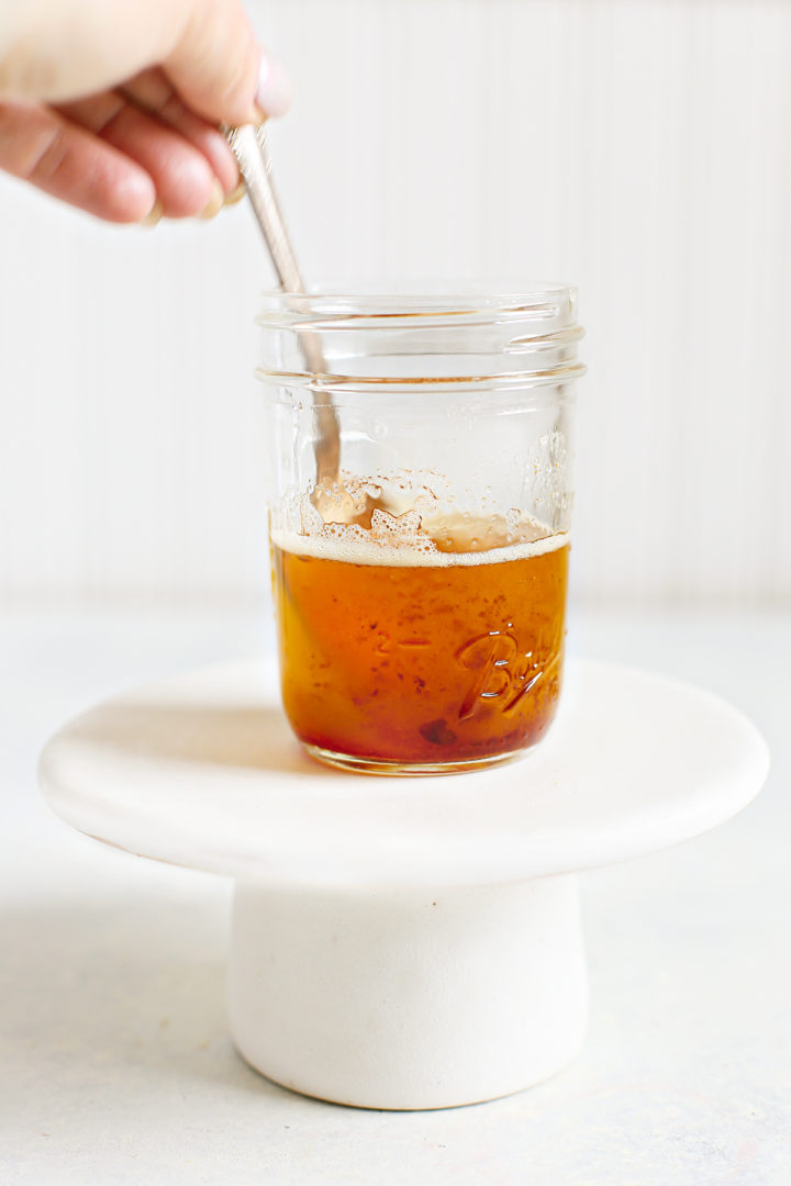 woman stirring a jar of browned butter