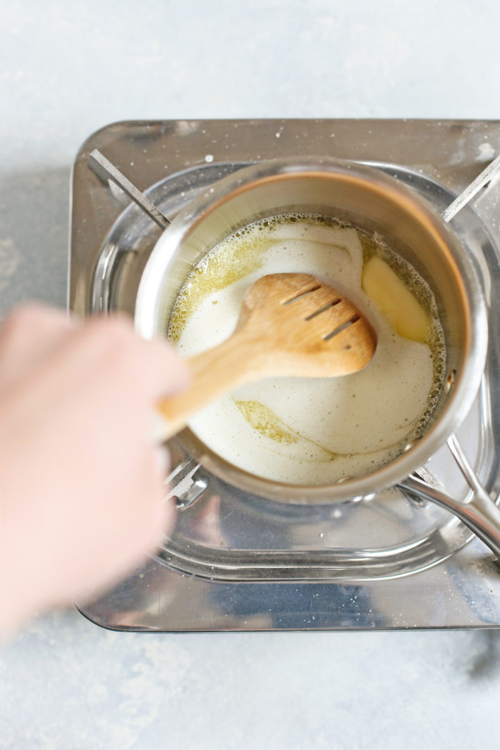 step 3 showing how to make brown butter - woman stirring butter as it melts in a saucepan