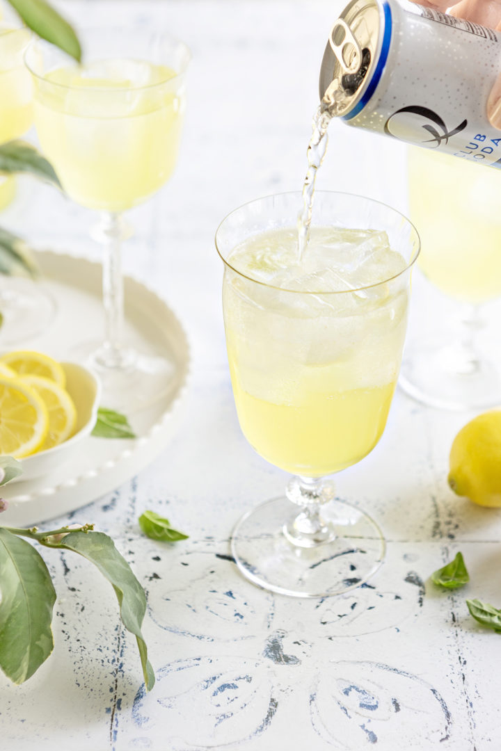 woman pouring club soda into a glass she she prepares a limoncello spritz with prosecco  