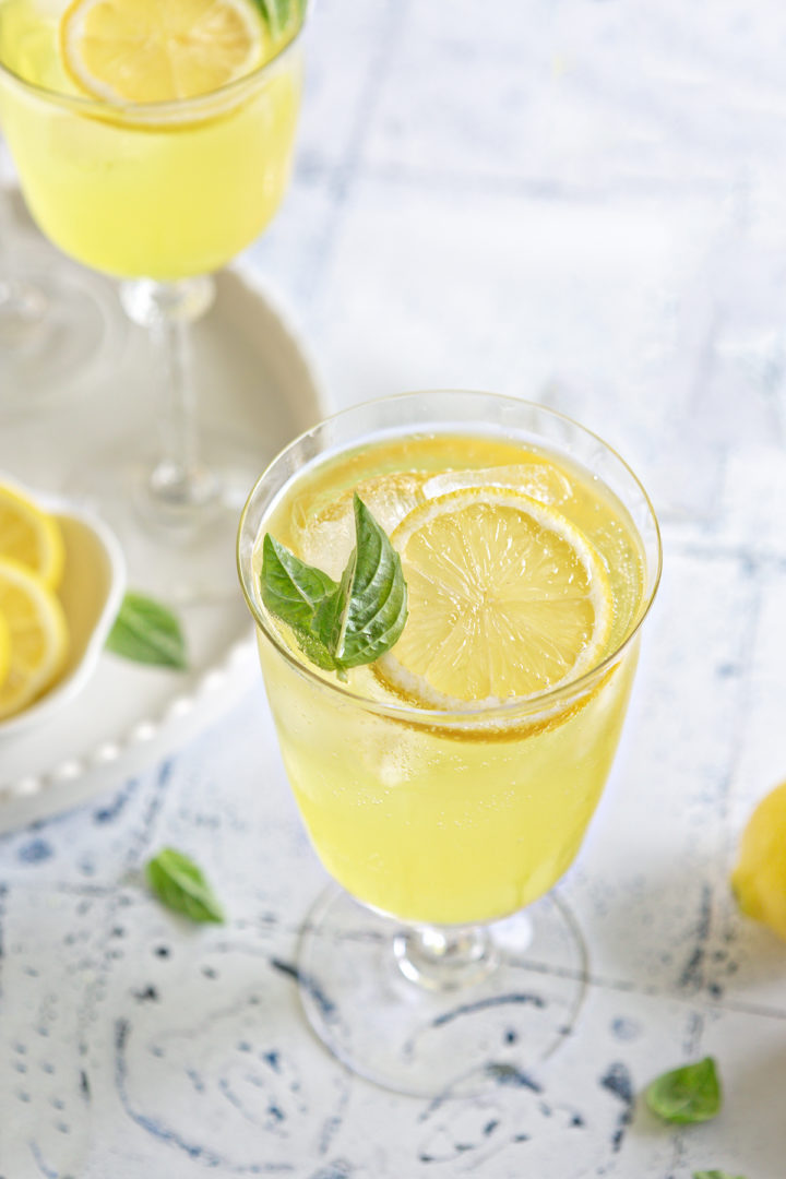 garnished limoncello spritz cocktail served in a balloon glass with a lemon slice and fresh basil