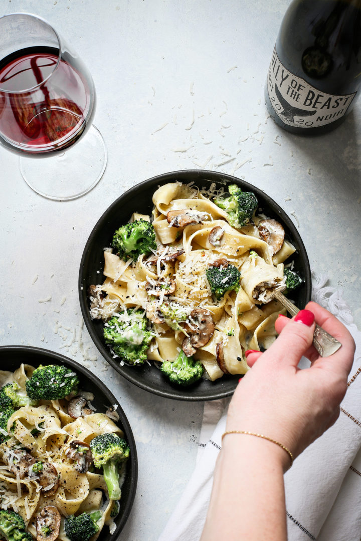 woman twirling pasta on her fork when eating alfredo pasta with mushrooms