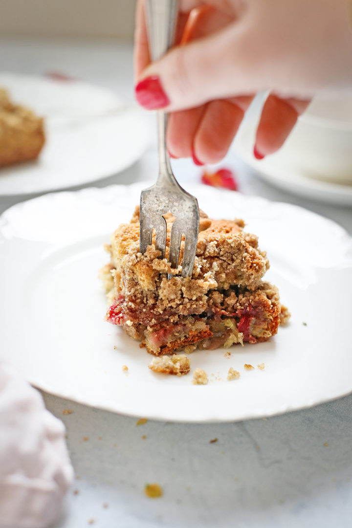 woman cutting into a slice of rhubarb coffee cake