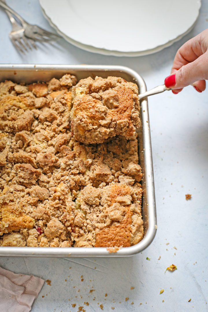 woman serving rhubarb coffee cake from the baking pan