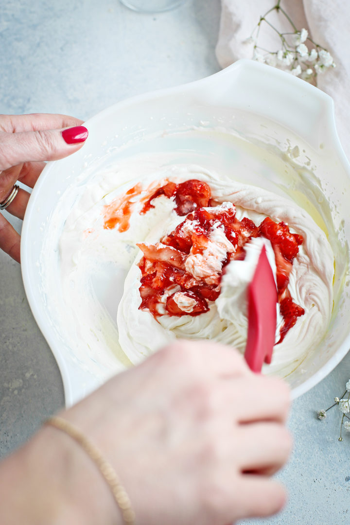 woman stirring strawberries with cream to make a strawberry fool dessert