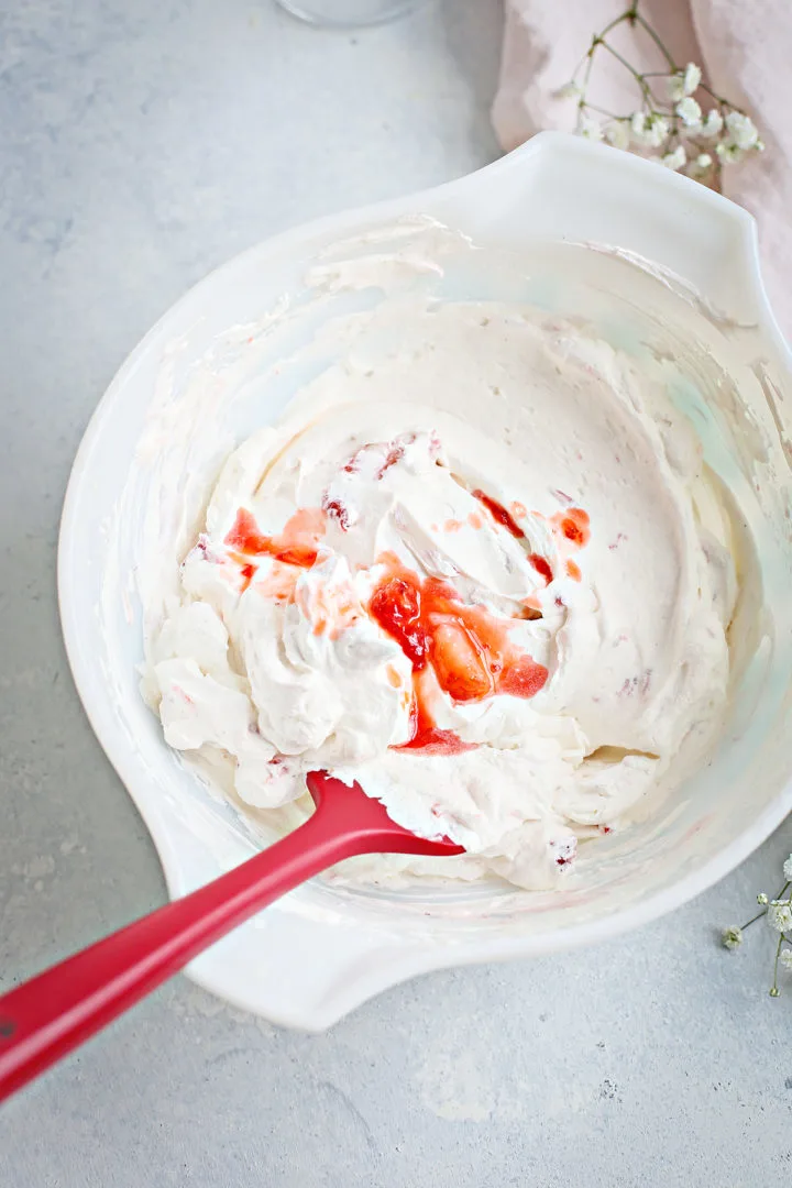 strawberry and cream sweet whipped cream in a white bowl with a red spatula