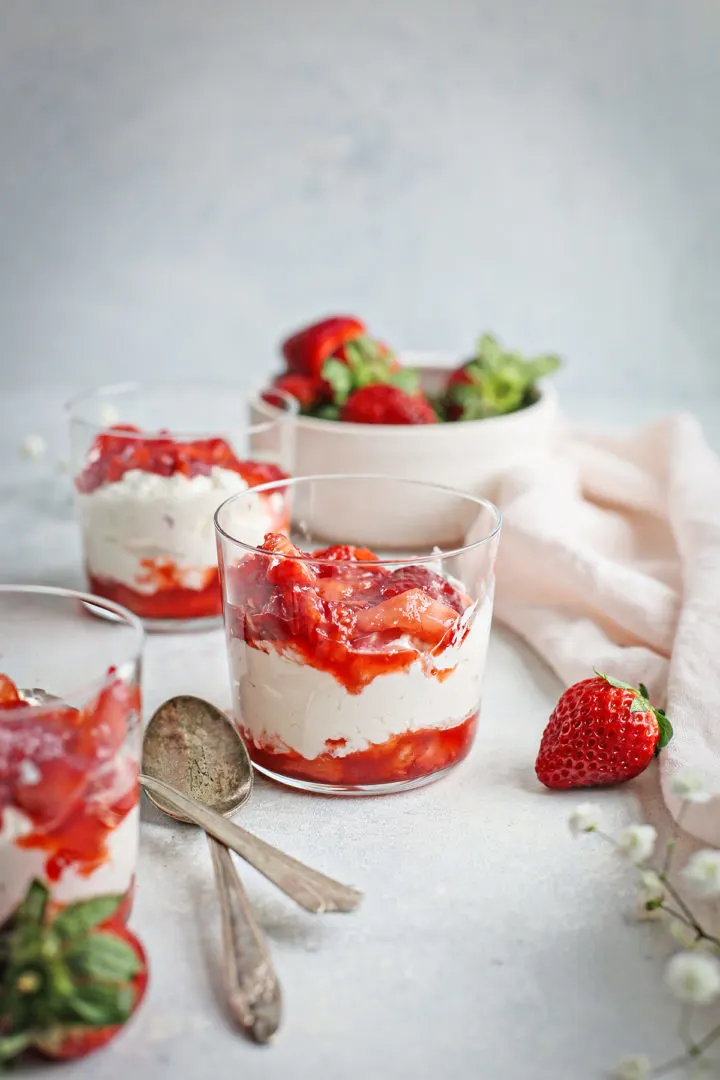 a clear dessert dish with a layer of strawberries, followed by a layer of strawberry whipped cream, and another layer of strawberries