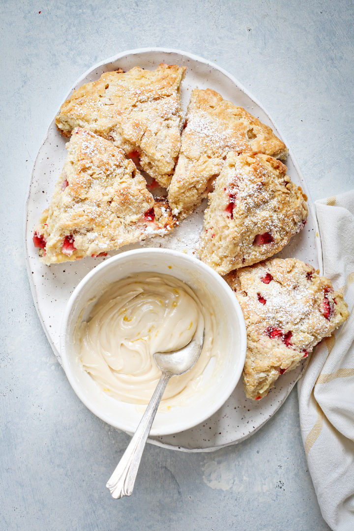 strawberry scones on a serving tray with a bowl of lemon glaze