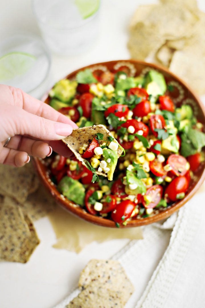 woman eating avocado corn salad with tortilla chips