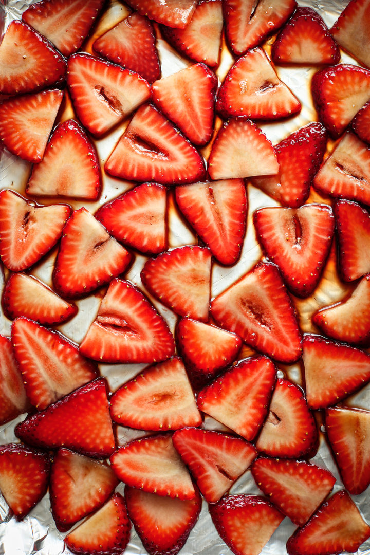 sliced strawberries with balsamic on a baking tray to make roasted strawberries for strawberry crostini