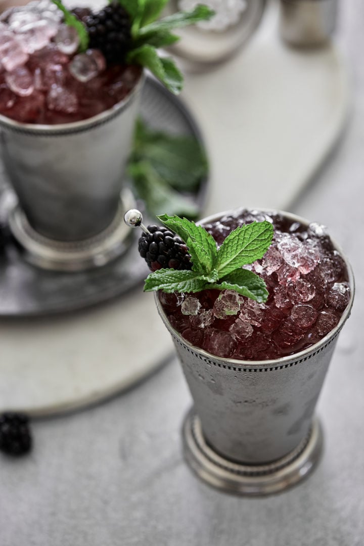 close up photo of a blackberry bourbon cocktail for derby day - a blackberry mint julep garnished with fresh mint and blackberry