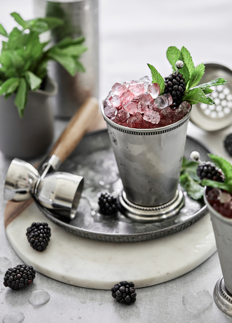 silver julep cup with a blackberry mint julep served on crushed ice and garnished with fresh mint