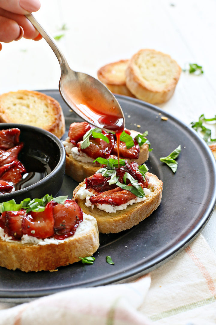 woman drizzling strawberry balsamic sauce on strawberry bruschetta before serving