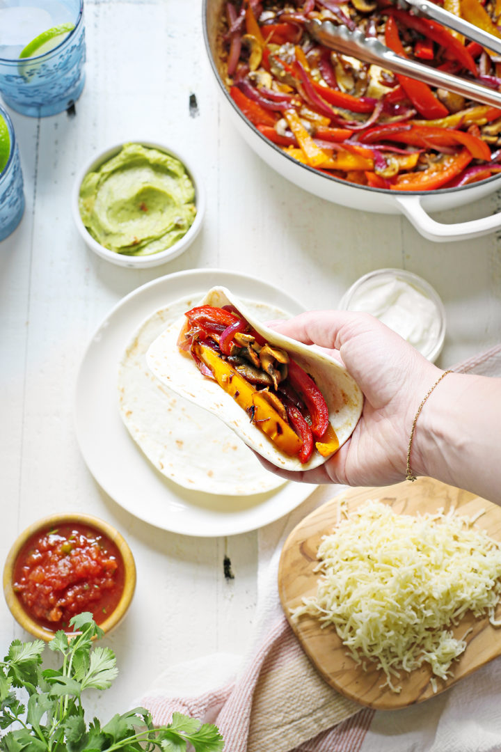 woman assembling her tortilla for this vegetable fajita recipe	