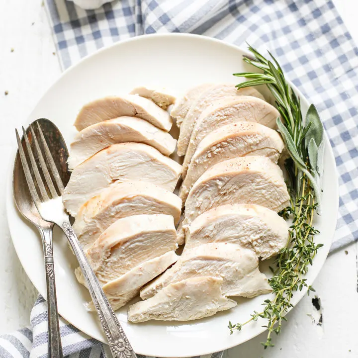 poached chicken on a white plate with fresh herbs