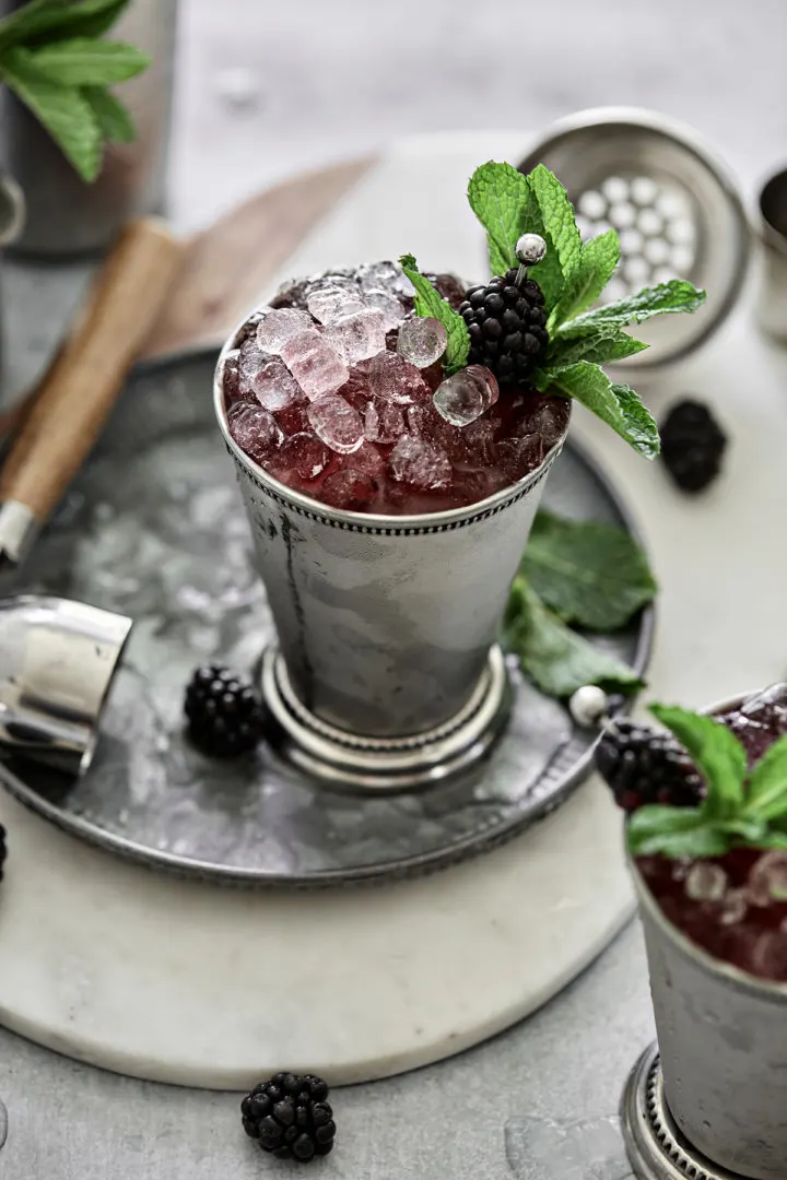 photo of kentucky derby cocktail recipe being served in mint julep cups with fresh blackberry mint garnish