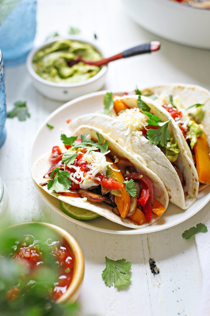 close up photo of a white plate with three vegetarian fajitas	